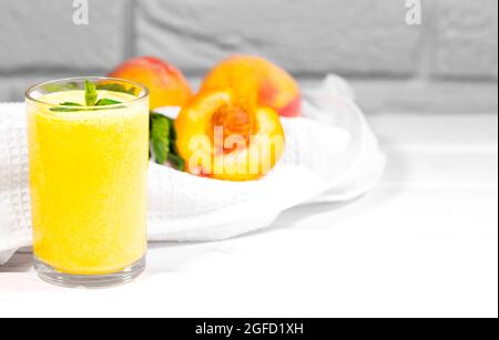 Smoothie mit Pfirsich und Minzblatt mit Stück Tuch auf weißem Backstein Hintergrund, horizontale Auflösung, gesunde Sommerdiät Stockfoto