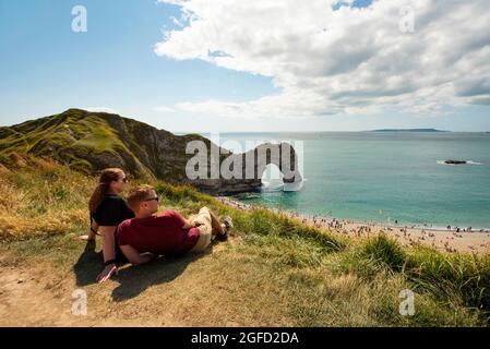 Durdle Door, die ikonischste Landschaft der Jurassic Coast mit ihrem natürlichen Kalksteinbogen. Menschen genießen einen sonnigen Sonntag. Dorset, Großbritannien. 22 August 2021 Stockfoto