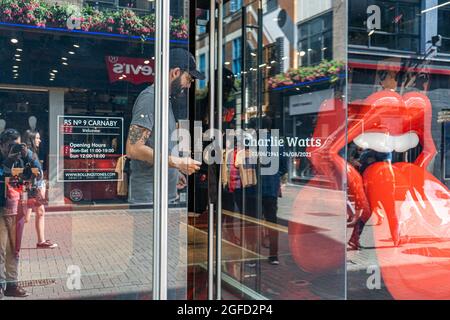 CARNABY STREET LONDON, GROSSBRITANNIEN. 25. August 2021. Ein Verkäuferin stellt Blck Ribbon vor die Tür des Rolling Stones Shops in der Carnaby Street als Hommage an den Rolling Stones Drummer Charlie Watts, der am Dienstag im Alter von 80 Jahren starb. Credit amer Ghazzal/Alamy Live News Stockfoto