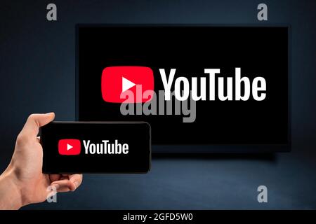 MOSKAU, RUSSLAND - 25. August 2021 : Internet-Service Youtube auf Telefon und tv-Bildschirm. Video-Hosting-Website. Nahaufnahme mans Hand hält ein Mobiltelefon w Stockfoto
