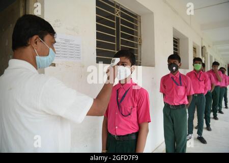 Agartala, Indiens nordöstlicher Bundesstaat Tripura. August 2021. Die Schüler der Netaji Subhas Vidyaniketan-Schule stellen sich an, um ihre Temperatur überprüfen zu lassen, bevor sie am ersten Tag der Wiedereröffnung von Schulen und Colleges nach der Entspannung in COVID-19-Beschränkungen in Agartala, der Hauptstadt des nordöstlichen indischen Bundesstaates Tripura, den 25. August 2021 in den Klassenzimmer eintreten. Quelle: Str/Xinhua/Alamy Live News Stockfoto