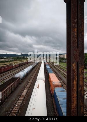 Güterzüge und Tankwagen auf einem Bahnhofsgelände unter Sturmwolken, aus industrieller Sicht gesehen. Stockfoto
