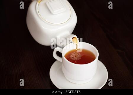 Tea Time: Weiße Teetasse und Teekannen auf schwarzem Hintergrund Stockfoto