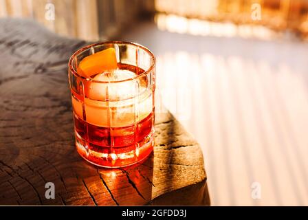 Negroni Cocktail auf einem dunklen Holztisch im Sonnenlicht. Mit Platz für Ihren Text Stockfoto
