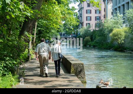 Zürich, Schweiz - 13. Juli 2019: Fußgänger auf einem schönen Fußweg entlang eines innerstädtischen Flusses Stockfoto