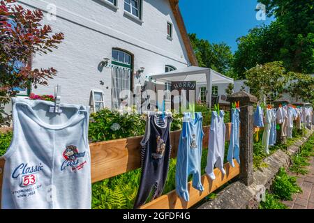 Babykleidung an der Wäscheleine im Vorgarten zu hängen, ist eine alte Traditon im Clountryside, Süderstapel, Schleswig-Holstein, Norddeutschland Stockfoto