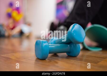Ein Paar blaue Hex-Hanteln aus hartem Kunststoff, die auf dem gummiverfilzten Boden eines Fitnessstudios oder Fitnessstudios liegen Stockfoto