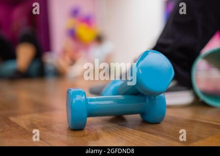 Ein Paar blaue Hex-Hanteln aus hartem Kunststoff, die auf dem gummiverfilzten Boden eines Fitnessstudios oder Fitnessstudios liegen Stockfoto