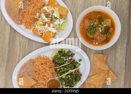 Verschiedene Teller auf dem Tisch mit Carne Asada Tacos, Enchiladas und Albondigas-Suppe zur Auswahl. Stockfoto