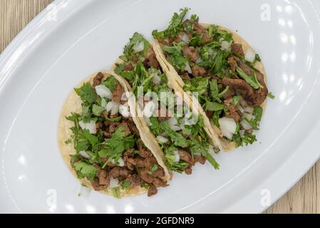 Blick von oben auf herzhafte Beilagen von Carne Asada Steak Street Tacos gefüllt mit Fleisch, Koriander und Zwiebeln. Stockfoto