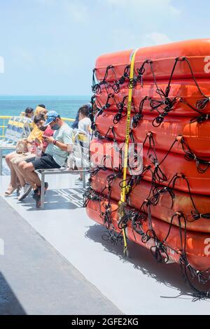 Eine Gruppe von Passagieren, die in der Nähe der Rettungsboote der Fähre in Mexiko sitzen. Selektiver Fokus, vertikaler Bildschirm. Stockfoto