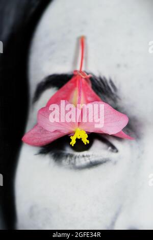 Das Gesicht einer Frau mit Blume über dem Augapfel. Stockfoto