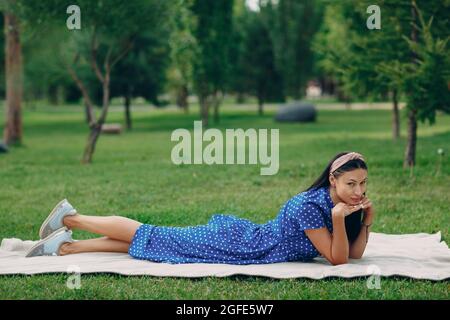 Schöne junge Erwachsene Frau in blauem Kleid Picknick auf der Wiese im Park. Stockfoto