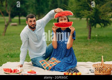 Junge Erwachsene Frau und Mann Paar Picknick auf der grünen Wiese im Park Spaß mit Wassermelone. Stockfoto