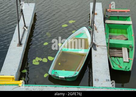 Die alten Fischerboote am Fluss sind am Pier gebunden und ungenutzt. Einige von ihnen voller Wasser. Stockfoto