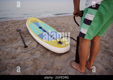 Nahaufnahme des Mannes bereitet sich auf die Paddelsurfen an einem Strand aufblasend supboard Stockfoto