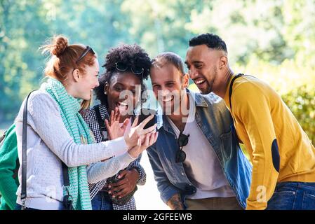 Glückliche junge Freunde mit Smartphone im öffentlichen Park Stockfoto