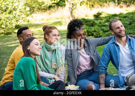 Glückliche junge Freunde sitzen zusammen im öffentlichen Park Stockfoto