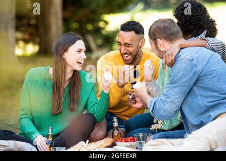 Glückliche junge Freunde beim Picknick im öffentlichen Park Stockfoto