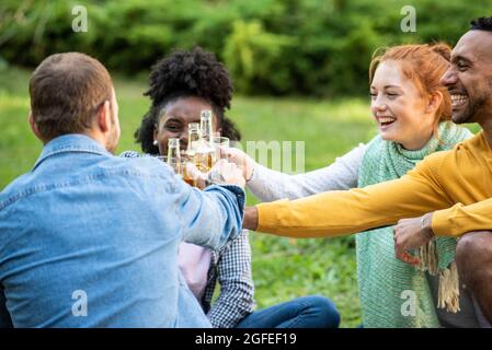 Fröhliche junge Freunde, die im Garten Getränke toasten Stockfoto