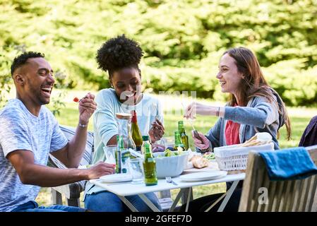 Lächelnde junge Freunde, die im Park essen Stockfoto
