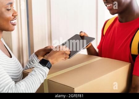 Die Dame Erhält Zu Hause Die Gelieferte Parzelle, Indem Sie Den Finger Auf Die Tablette Legt Stockfoto