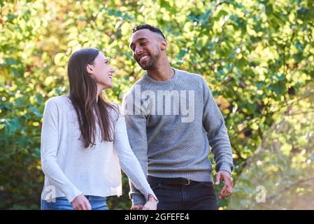 Lächelndes junges Paar, das sich im öffentlichen Park ansieht Stockfoto