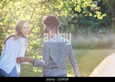 Lächelnde junge Freunde, die im öffentlichen Park spazieren Stockfoto