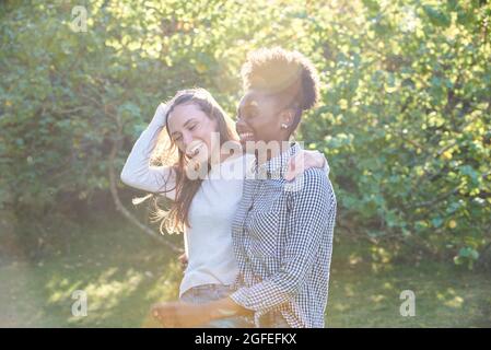 Lächelnde junge Freunde, die im öffentlichen Park spazieren Stockfoto