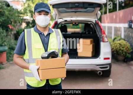 Asiatischer Entlieferer hält maskierte Boxen, um die Ausbreitung des Coronavirus oder COVID-19 zu verhindern Stockfoto