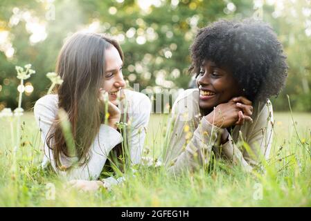 Porträt lächelnder junger Freundinnen, die im Park liegen Stockfoto