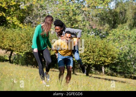 Lächelnde junge Freunde, die Spaß beim Spaziergang im öffentlichen Park haben Stockfoto
