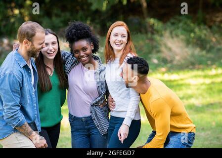 Lächelnde Gruppe von Freunden, die Spaß im öffentlichen Park haben Stockfoto