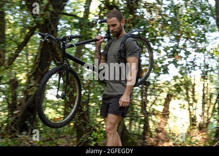 Junger Mann mit Fahrrad im Wald Stockfoto