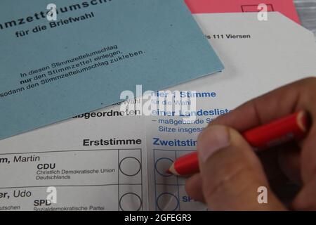 Viersen, Deutschland - August 20. 2021: Nahaufnahme des deutschen Stimmzettels für die Briefwahl mit Umschlägen und Hand mit rotem Bleistift (Schwerpunkt auf der Mitte von le Stockfoto