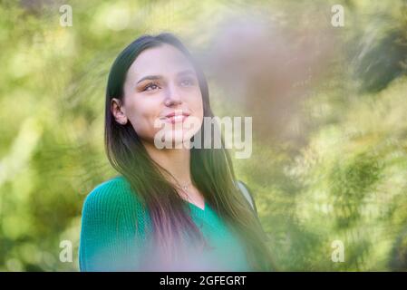 Nachdenkliche junge Frau, die im öffentlichen Park steht Stockfoto