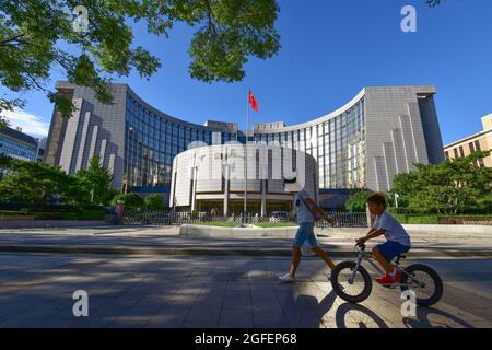 Peking, China. August 2021. Ein Kind fährt am Hauptsitz der chinesischen Volksbank in Peking vorbei.die chinesische Volksbank ist die Zentralbank der Volksrepublik China, die für die Durchführung der Geldpolitik und die Regulierung von Finanzinstituten auf dem chinesischen Festland verantwortlich ist. Wie durch das Volksbankgesetz und das Handelsbankgesetz festgelegt. Kredit: SOPA Images Limited/Alamy Live Nachrichten Stockfoto