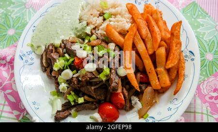 Hausgemachter peruanischer Lomo Saltado mit Aji-Sauce auf dem Teller Stockfoto