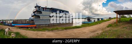 Amazonas, Peru - 07. Dezember 2019: Blick auf das langsame Boot 'Maria Fernanda' und Regenbogen im kleinen Hafen am Amazonas. Amazonien. Südamerika Stockfoto