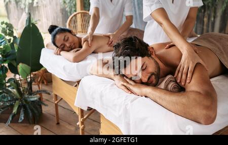 Paarmassage im Spa Resort. Wunderschönes Paar, das eine Rückenmassage im Freien bekommt, romantisches Wochenende und Entspannung Stockfoto