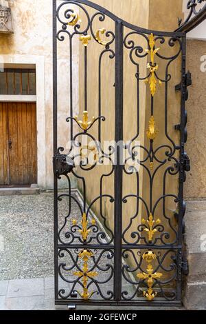 Ein altes halboffenes schmiedeeisernes Tor in einem Schloss. Stockfoto