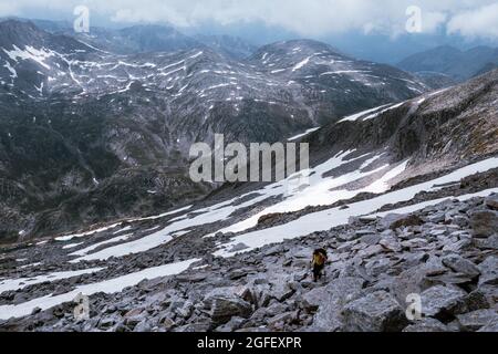 Frau, die einen felsigen Berg hinauf zum Gipfel wandert Stockfoto