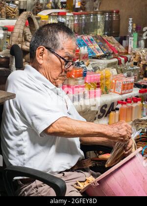 Iquitos, Peru - Dez 2019: Porträt eines alten Mannes, der auf dem Stuhl sitzt und verschiedene Dinge verkauft, die der Belen Basar (Belén Markt), Iquitos - Tor zu Stockfoto