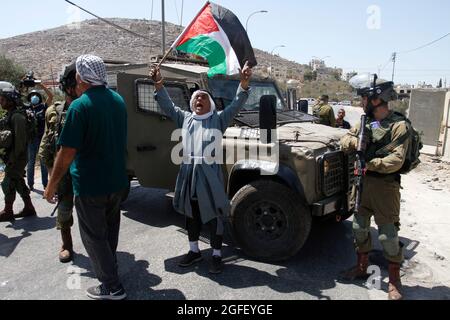 Nablus, Palästina. August 2021. Ein Protestler singt Slogans, während er während der Demonstration eine Flagge hält. Palästinenser protestieren gegen den Bau einer neuen Straße für israelische Siedler und fordern auch die Entfernung des israelischen Außenpostens Eviatar in der Nähe von Beita, südlich von Nablus im Westjordanland. Kredit: SOPA Images Limited/Alamy Live Nachrichten Stockfoto