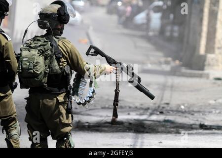 Nablus, Palästina. August 2021. Ein israelischer Soldat feuert während der Demonstration Tränengas auf palästinensische Demonstranten. Palästinenser protestieren gegen den Bau einer neuen Straße für israelische Siedler und fordern auch die Entfernung des israelischen Außenpostens Eviatar in der Nähe von Beita, südlich von Nablus im Westjordanland. Kredit: SOPA Images Limited/Alamy Live Nachrichten Stockfoto