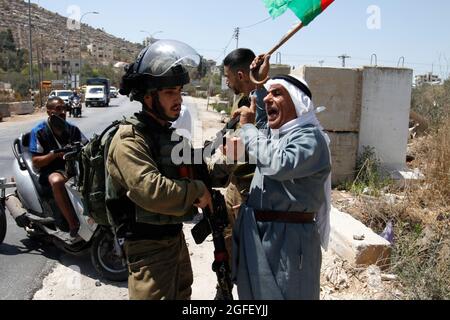 Nablus, Palästina. August 2021. Ein Protestler singt Slogans, während er während der Demonstration einem israelischen Soldaten gegenübersteht. Palästinenser protestieren gegen den Bau einer neuen Straße für israelische Siedler und fordern auch die Entfernung des israelischen Außenpostens Eviatar in der Nähe von Beita, südlich von Nablus im Westjordanland. Kredit: SOPA Images Limited/Alamy Live Nachrichten Stockfoto