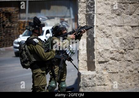 Nablus, Palästina. August 2021. Ein israelischer Soldat feuert während der Demonstration Tränengas auf palästinensische Demonstranten. Palästinenser protestieren gegen den Bau einer neuen Straße für israelische Siedler und fordern auch die Entfernung des israelischen Außenpostens Eviatar in der Nähe von Beita, südlich von Nablus im Westjordanland. Kredit: SOPA Images Limited/Alamy Live Nachrichten Stockfoto