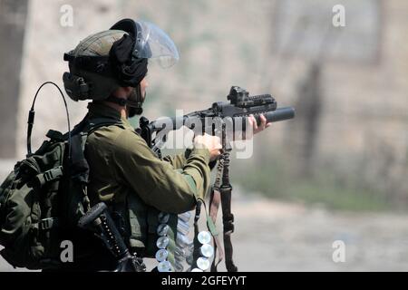 Nablus, Palästina. August 2021. Ein israelischer Soldat feuert während der Demonstration Tränengas auf palästinensische Demonstranten. Palästinenser protestieren gegen den Bau einer neuen Straße für israelische Siedler und fordern auch die Entfernung des israelischen Außenpostens Eviatar in der Nähe von Beita, südlich von Nablus im Westjordanland. (Foto von Nasser Ishtayeh/SOPA Images/Sipa USA) Quelle: SIPA USA/Alamy Live News Stockfoto