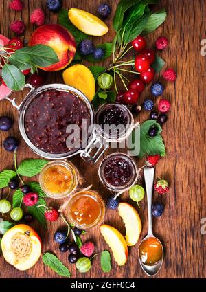 Marmelade aus verschiedenen Beeren in Gläsern auf rustikalem Holzhintergrund. Stockfoto