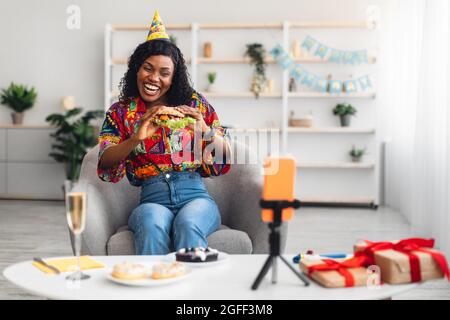 Black Woman Video Calling Auf Geburtstag Essen Burger Zu Hause Stockfoto